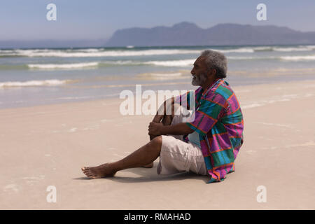 Riflessivo senior uomo seduto sulla spiaggia Foto Stock