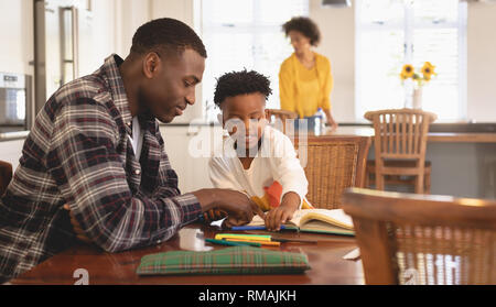 African American padre aiutando il suo figlio con i compiti a tavola Foto Stock