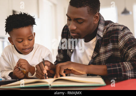 African American padre aiutando il suo figlio con i compiti a tavola Foto Stock