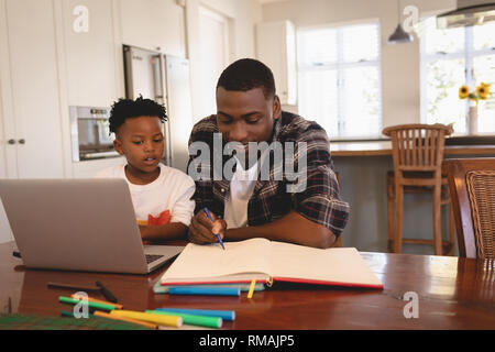 African American padre aiutando il suo figlio con i compiti a tavola Foto Stock