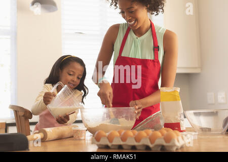 African American madre e figlia la miscelazione a secco e a umido ingredienti insieme in cucina Foto Stock