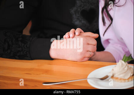 Giovane bella giovane è in possesso di ogni altro le mani in un cafe'. Foto Stock