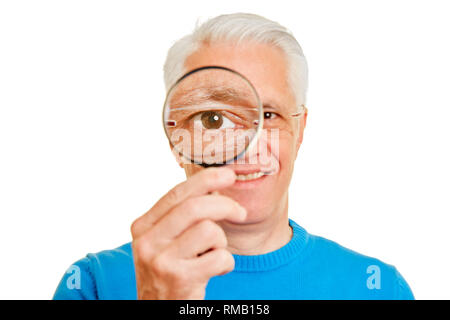 Il vecchio uomo guarda con occhio attraverso la lente di ingrandimento come un concetto di verifica Foto Stock
