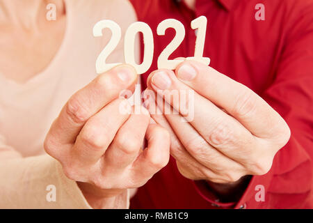 Due mani senior visualizza l'anno 2021 come un numero Foto Stock