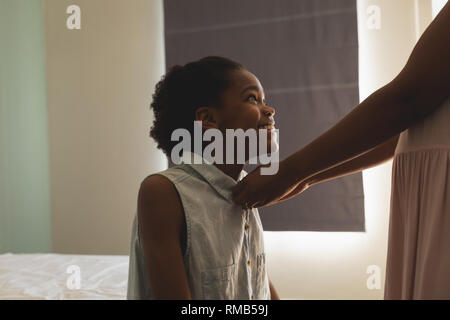African American madre aiutando a sua figlia di indossare un panno in camera da letto Foto Stock