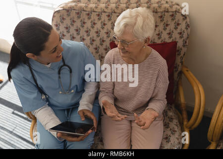 Angolo di alta vista del medico donna discutendo relazione medica con i senior donna sulla tavoletta digitale Foto Stock