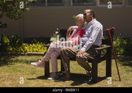 Vista laterale della coppia senior rilassante sulla panchina nel giardino Foto Stock