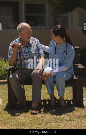 Giovani donne medico parlando con i senior uomo mentre seduta sul banco di lavoro Foto Stock