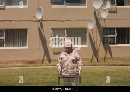 Disabili donna senior a piedi con walker in giardino Foto Stock