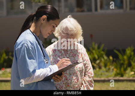 Giovani donne medico discutendo relazione medica con i senior donna Foto Stock