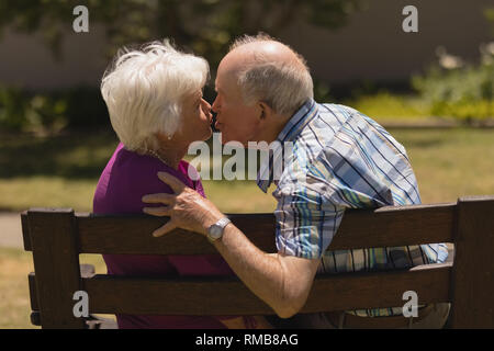 Coppia senior kissing ogni altro nel parco Foto Stock
