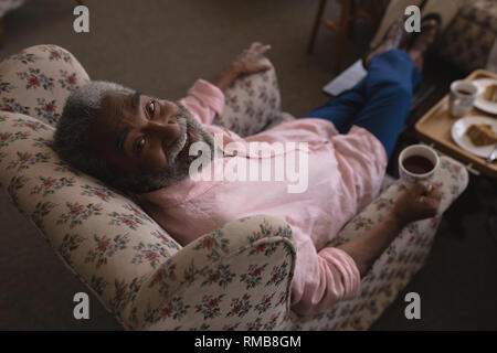 L'uomo anziano avente nero caffè nella stanza vivente Foto Stock
