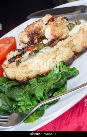 Cavolfiore arrosto di manzo servita con Spinaci appassito e pomodoro grigliate Foto Stock
