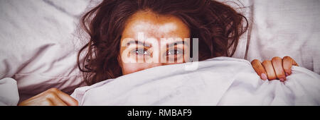 La donna che si nasconde sotto una coperta per letto Foto Stock