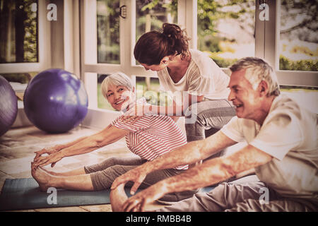 Trainer femmina assistere coppia senior in esecuzione di esercizio Foto Stock