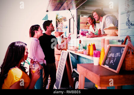 Sorridente cameriere facendo ordine dal giovane Foto Stock