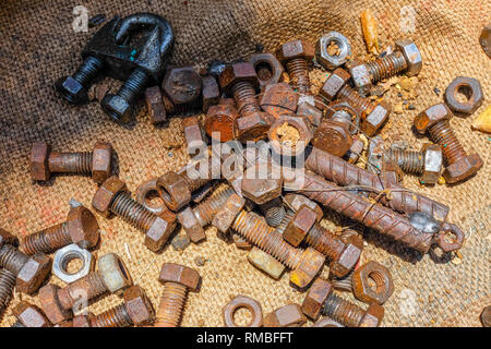 Molto di dadi e bulloni closeup, su un letto di sacco Foto Stock