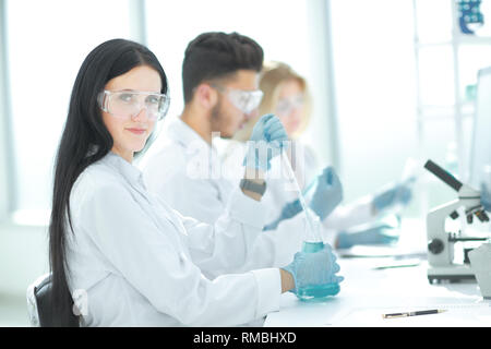 Close up.moderna donna seduta con i colleghi al tavolo di laboratorio. Foto Stock