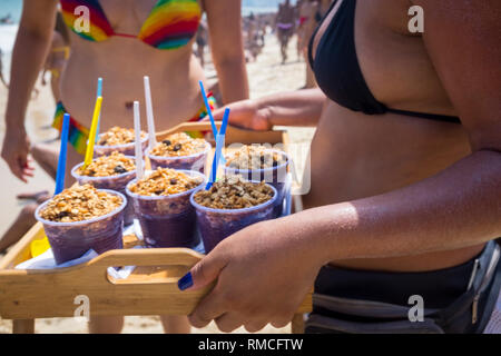 Close-up di un vassoio di carni congelate Acai berry snack serviti con granola da un irriconoscibile la donna in un bikini sulla spiaggia di Ipanema a Rio de Janeiro in Brasile Foto Stock