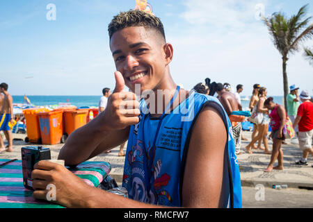 RIO DE JANEIRO - Gennaio 20, 2015: un giovane brasiliano venditore a vendere la birra da un raffreddatore dà un sorridente pollice fino al Carnevale street party in Ipanema Foto Stock