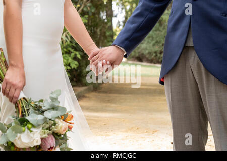 Matura in amore stringono le mani, ella con bouquet di fiori Foto Stock