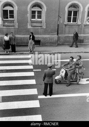 Un funzionario di polizia si ferma uno scooter di fronte un crosswalk. Foto Stock