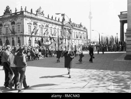 Il viale Unter den Linden in Berlino Est: persone con bandiere e striscioni sul loro modo al maggio al Rally di Marx-Engels-Platz (Schlossplatz), sulla sinistra la Zeughaus con il Museo Storico Tedesco e sullo sfondo la Fernsehturm nella nebbia. Foto Stock