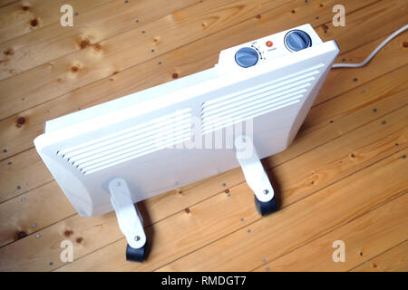 Lavoro elettrico bianco termoconvettore con il pannello di controllo sulla parte superiore su pavimento di legno in una stanza della casa vista superiore closeup Foto Stock