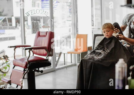 Barbiere dando scarti da ragazzo adorabile Foto Stock