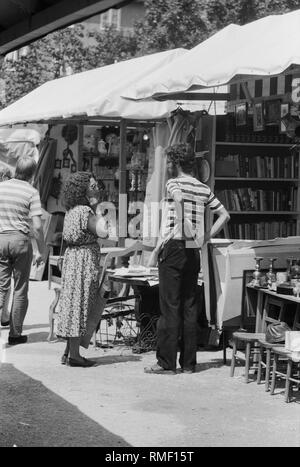 Un venditore di un mercato in stallo la Auer Dult a Monaco di Baviera in una conversazione con un cliente. Foto Stock