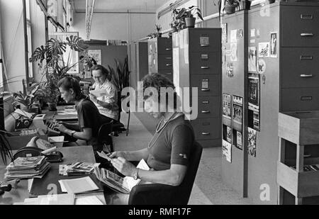 I dipendenti dell'archivio di immagini del Sueddeutscher Verlag ricerca immagini. In primo piano una giovane donna è in cerca di una pila di foto. Foto Stock