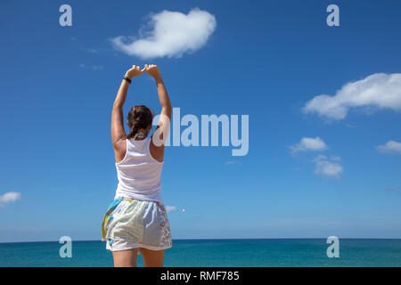 Donna con aumentato le mani vicino al mare Foto Stock