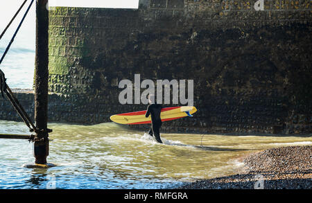Brighton, Regno Unito. 15 Feb, 2019. Un surfista entra nel mare di spiaggia di Brighton oggi in un giorno caldo e soleggiato come la previsione è per di più della stessa durante il fine settimana del credito: Simon Dack/Alamy Live News Foto Stock