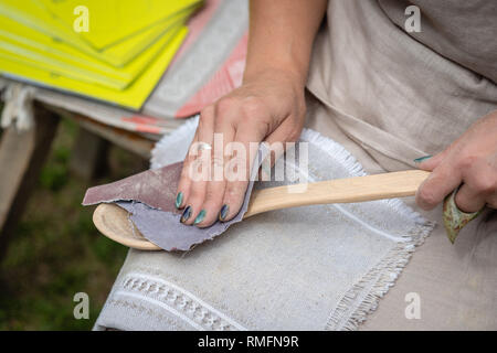 La donna rende artigianato tradizionale cucchiaio di legno. - Immagine Foto Stock