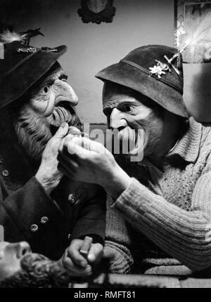 Due uomini in costumi tradizionali che indossa il vecchio Werdenfelser scolpito a mano le maschere in legno. Foto Stock