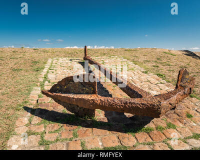 Un grande rusty anchor giacente a terra e cielo blu in estate (Francia) Foto Stock