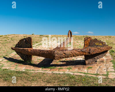 Un grande rusty anchor giacente a terra e cielo blu in estate (Francia) Foto Stock