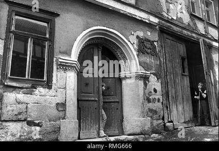 La foto mostra un ingresso di casa in Schleusingen, nell'ex RDT, da cui un ragazzo è di uscire. In corrispondenza del bordo della foto di un altro bambino è in piedi in un cortile d'ingresso appoggiato su un bastone. Foto Stock
