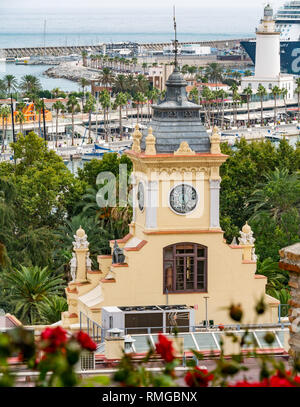 Turista nave in porto con il faro e orange Town Hall clock tower, Malaga, Andalusia, Spagna Foto Stock