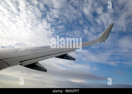 La splendida vista dal passeggero aereo supersonico finestra alta in movimento da destra verso sinistra contro la luce in un cielo blu con nuvole bianche Foto Stock