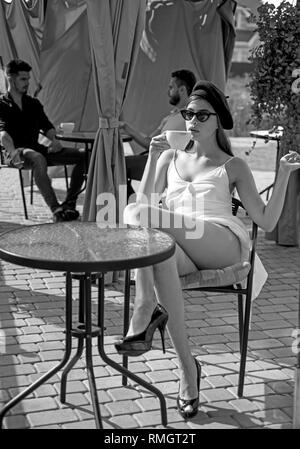 Iniziare da annusare il profumo prima della degustazione. Pretty Woman bere il caffè in outdoor cafe. Donna godere di bere il caffè espresso o cappuccino. Adorabili donna in Foto Stock