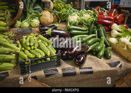 Verde di generi alimentari comprese le zucchine, melanzane, asparagi, peperoni rossi e i broccoli in vendita su una verdura in stallo un allevatore locale mercato. Foto Stock