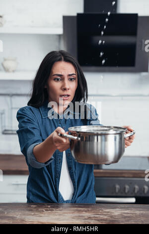 Preoccupati piuttosto Donna con vaso ha a che fare con la perdita di acqua in cucina Foto Stock