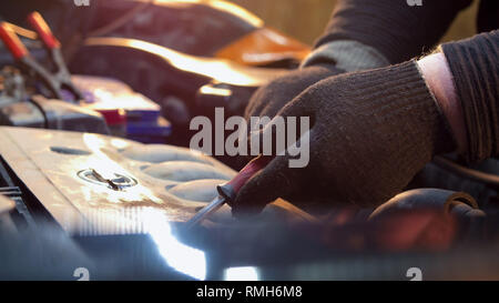 Servizio auto. Uomo meccanico svitando la parte superiore di un motore Foto Stock