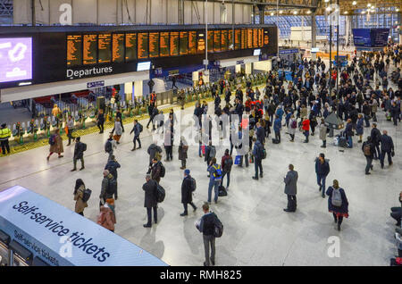 Londra, Feb 13, 2019: molte persone di fronte alla scheda ora in ora di punta alla stazione ferroviaria di Waterloo, London, England.la stazione di Waterloo, Londra centrale ra Foto Stock