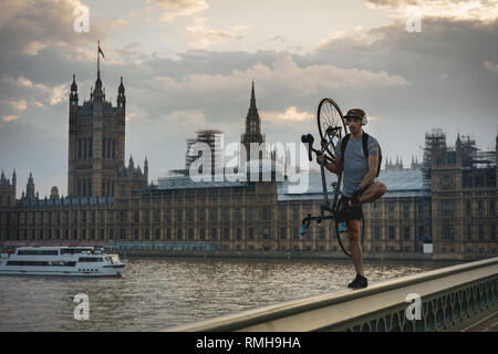 London, Regno Unito - Aprile, 2018. Un giovane di Acrobat con una bicicletta sulla balaustra del Westminster Bridge. Foto Stock