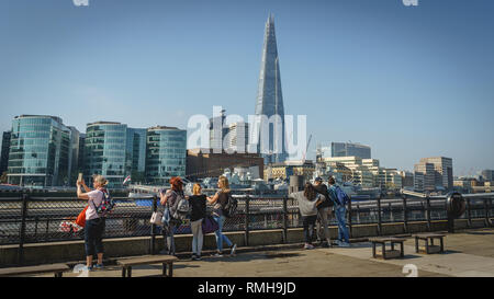 London, Regno Unito - Febbraio, 2019. I turisti sulla sponda nord del fiume Tamigi con il frammento e la più Londra Estate sullo sfondo. Foto Stock