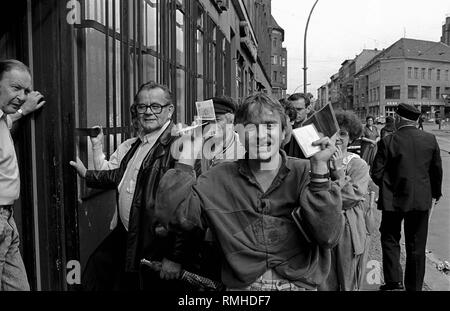 Germania Berlino, 1 Luglio 1990: l'uomo con il marco tedesco e un GDR scheda ID nel giorno della moneta europea, la Sparkasse Rosenthaler Strasse. Foto Stock