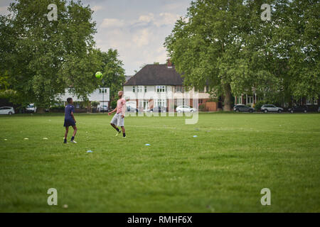 London, Regno Unito - Giugno, 2018. Due giovani uomini a giocare a calcio in un parco a sud-est di Londra. Foto Stock