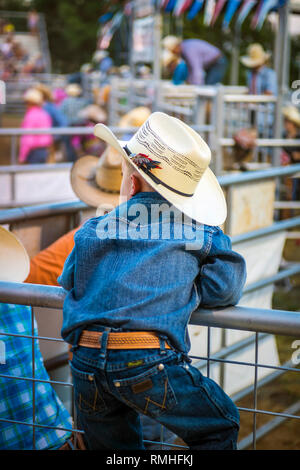 Giovani cowboy standing sulla recinzione guardando un rodeo in Texas USA Foto Stock